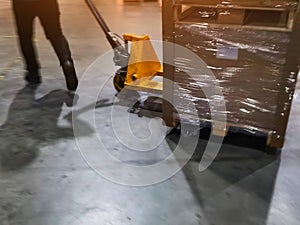 Worker driving forklift loading shipment carton boxes goods on wooden pallet at loading dock from container truck to warehouse car