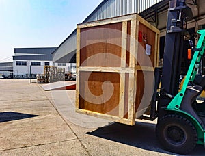 Worker driving forklift loading shipment carton boxes goods on wooden pallet at loading dock from container truck to warehouse car