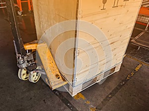 Worker driving forklift loading and unloading shipment carton boxes and goods on wooden pallet from container truck to warehouse