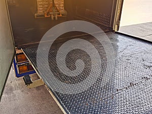 Worker driving forklift loading and unloading shipment carton boxes and goods on wooden pallet from container truck to warehouse c