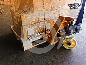 Worker driving forklift loading and unloading shipment carton boxes and goods on wooden pallet from container truck to warehouse c