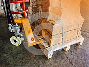 Worker driving forklift loading and unloading shipment carton boxes and goods on wooden pallet from container truck to warehouse c