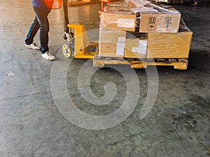 Worker driving forklift loading and unloading shipment carton boxes and goods on wooden pallet from container truck to warehouse c