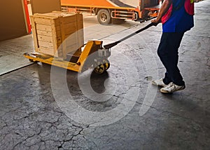 Worker driving forklift loading and unloading shipment carton boxes and goods on wooden pallet from container truck to warehouse c