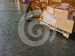 Worker driving forklift loading and unloading shipment carton boxes and goods on wooden pallet from container truck to warehouse c