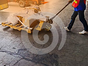 Worker driving forklift loading and unloading shipment carton boxes and goods on wooden pallet from container truck to warehouse c