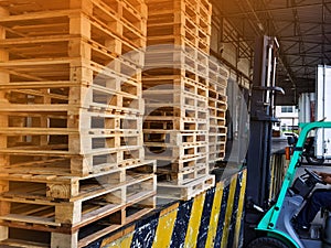 Worker driving forklift loading and unloading shipment carton boxes and goods on wooden pallet from container truck to warehouse c