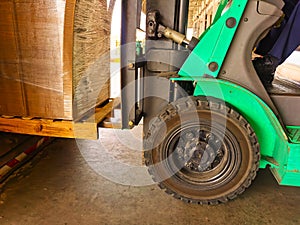 Worker driving forklift loading and unloading shipment carton boxes and goods on wooden pallet from container truck to warehouse c