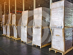 Worker driving forklift loading and unloading shipment carton boxes and goods on wooden pallet from container truck to warehouse c