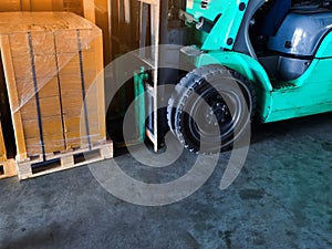 Worker driving forklift loading and unloading shipment carton boxes and goods on wooden pallet from container truck to warehouse c