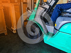 Worker driving forklift loading and unloading shipment carton boxes and goods on wooden pallet from container truck to warehouse c