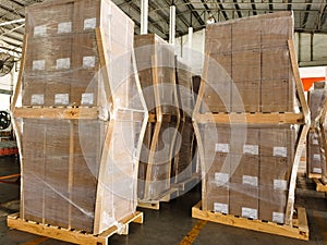 Worker driving forklift loading and unloading shipment carton boxes and goods on wooden pallet from container truck to warehouse c