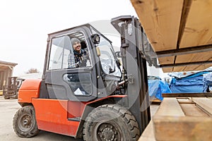 Worker driving forklift in lumber yard