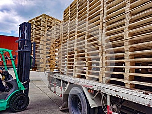 Worker driving forklift to loading and unloading wooden pallets from truck to warehouse cargo storage, shipment in logistics and