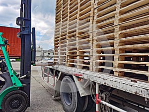 Worker driving forklift to loading and unloading wooden pallets from truck to warehouse cargo storage, shipment in logistics and