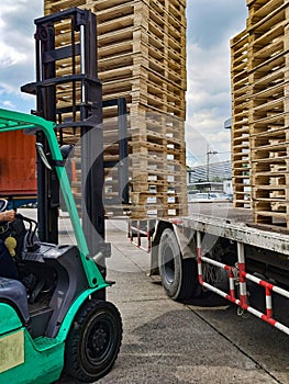 Worker driving forklift to loading and unloading wooden pallets from truck to warehouse cargo storage, shipment in logistics and