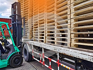 Worker driving forklift to loading and unloading wooden pallets from truck to warehouse cargo storage, shipment in logistics