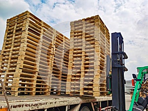 Worker driving forklift to loading wooden pallets from truck to warehouse cargo storage, shipment in logistics and transportation