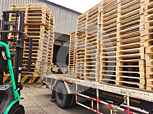 Worker driving forklift truck to unload wooden pallets stack from truck to the cargo warehouse to support shipment for logistics a