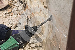 Worker with electrical hammer cleaning red brick wall