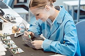 Worker in electronics manufacturing soldering a component