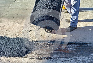 Worker empties a wheelbarrow containing asphalt photo