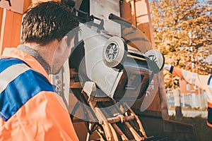 Worker emptying dustbin into waste vehicle