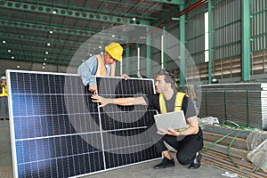 Worker and engineer checking solar panel in warehouse.