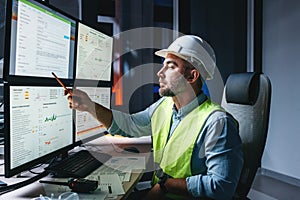 Worker engineer control process of production uses computer with modern SCADA system which showing AI and machine learning