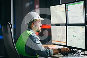 Worker engineer control process of production uses computer with modern SCADA system which showing AI and machine learning