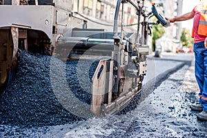 Worker or engineer operating an ashphalt paving machine