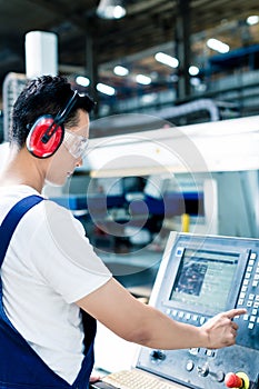 Worker entering data in CNC machine at factory