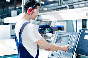Worker entering data in CNC machine at factory photo
