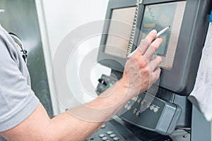 Worker entering data on screen of a modern machine tool in factory