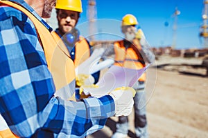 Worker examining a building plan while standing at construction site