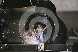 Worker at the factory in the helmet is of iron in the welding pr