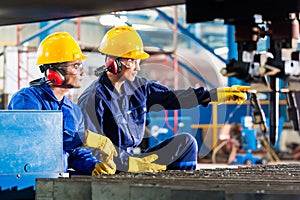 Worker in factory at industrial metal cutting machine