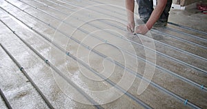 The worker fastens pipes for a heat-insulated floor to isolation, Installation works Underfloor heating pipes for water