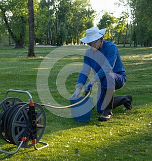 A worker fills water into a bucket,maintaining the greenery image