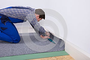 Worker Fitting Carpet On Floor photo