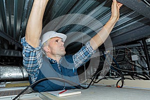 Worker fixing ceiling panel in building