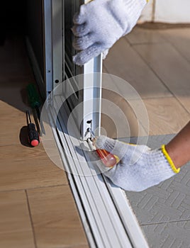 Worker fixing derailed roller of sliding door. Replace Sliding Glass Door Rollers concept