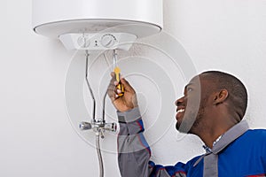 Worker Fixing Electric Boiler With Screwdriver