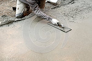 Worker flattening cement mortar on floor