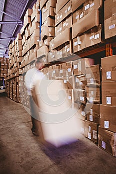 Worker with fork pallet truck stacker in warehouse