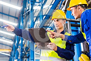 Worker and forklift driver in industrial factory