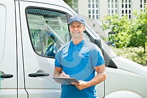 Worker In Front Of Truck Writing On Clipboard