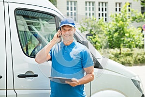 Worker In Front Of Truck Writing On Clipboard