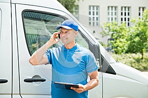 Worker In Front Of Truck Writing On Clipboard