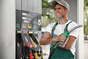 Worker with fuel pump nozzle at modern gas station